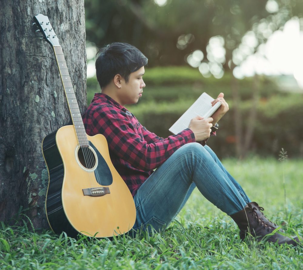 Asian handsome man with acoustic guitar at park